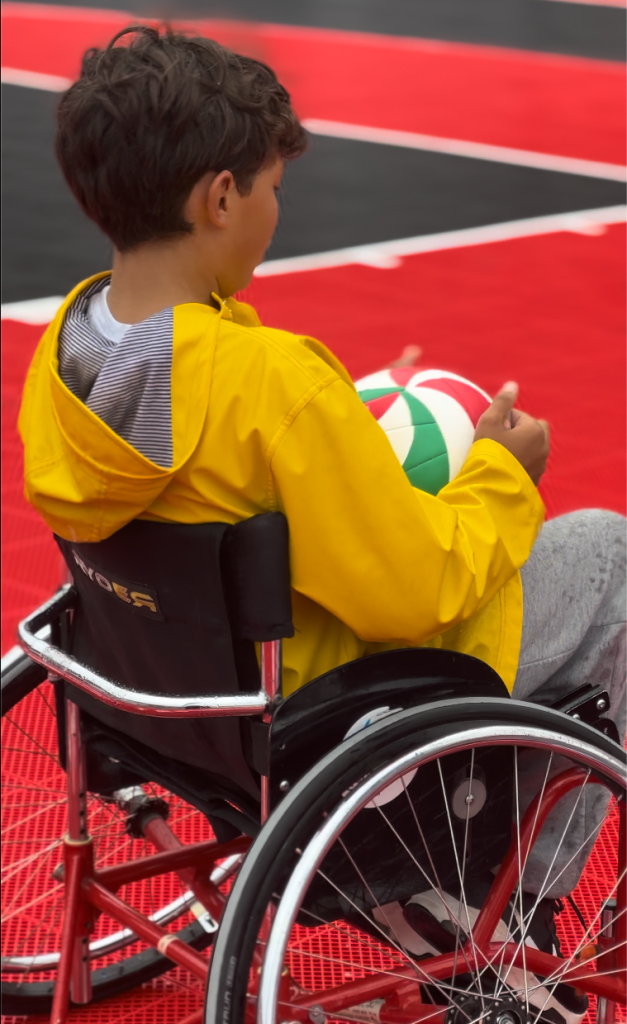 Garçon dans un fauteuil roulant qui tient un ballon de basketball.